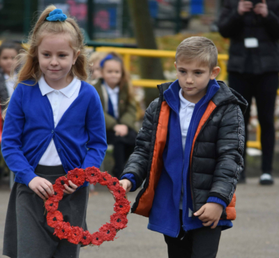 Two children carrying a poppy wreathe
