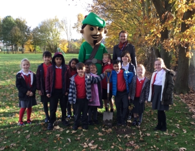 A group of children stood with Robin Hood outside on a field