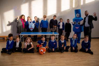 A group of children with a Rabbi standing around a Menorah