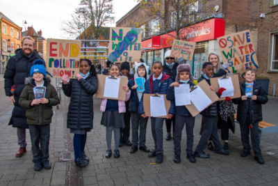 Children holding signs and clipboards demonstrating environmental change